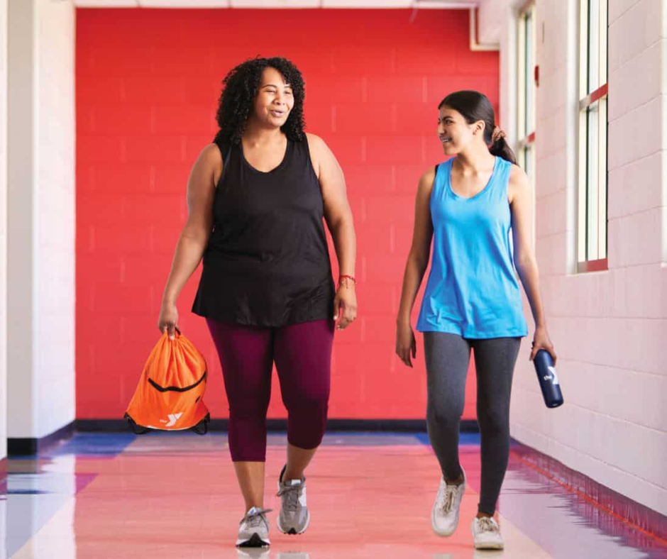 two women walking down a gym hallway