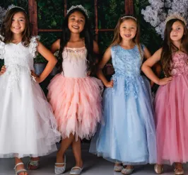 Four young girls standing side by side, wearing princess dresses and tiaras